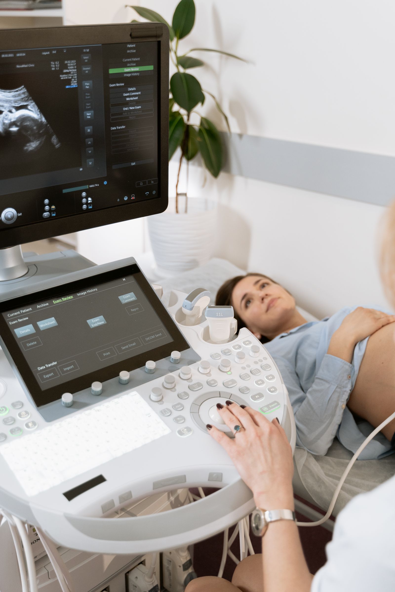 Médica realizando exame de ultrassom em uma gestante deitada na maca, com o aparelho em primeiro plano