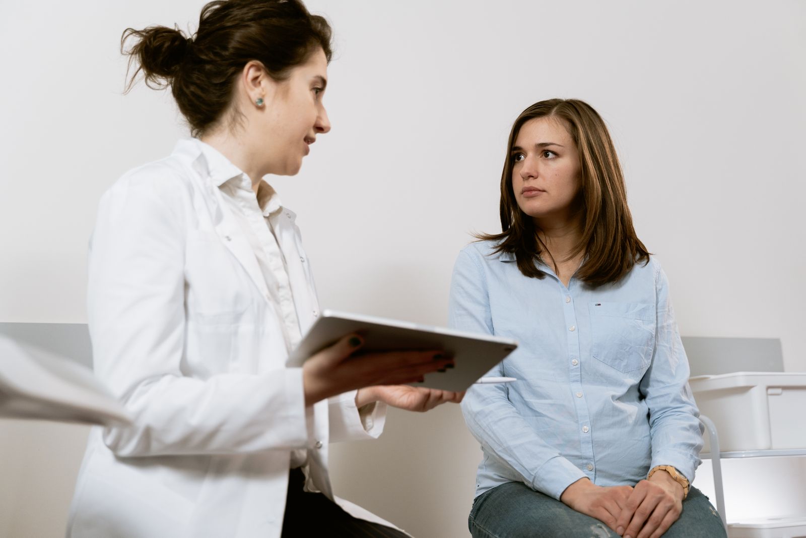 Médica de jaleco branco conversando com paciente durante consulta na clínica